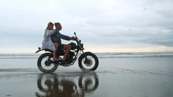 若い美しいカップルのヒップスターは、ビーチでレトロなバイクに乗って、屋外の肖像画、乗馬男と女の子、一緒に旅行、海、海 — ストック動画