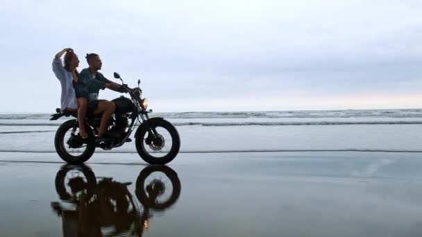 Unga vackra par hipsters rida retro motorcykel på stranden, utomhus porträtt, ridning kille och flicka, resa tillsammans, hav, hav — Stockvideo