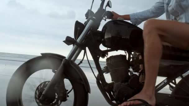 Hombre en moto a caballo en la playa. moto de época en la playa puesta de sol en Bali. Joven hipster masculino disfrutando de libertad y estilo de vida activo, divirtiéndose en un tour de ciclistas — Vídeos de Stock