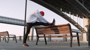 Genç adam koşmadan önce köprünün altında kolunu kaslarını geriyor. Yakışıklı atlet erkek germe egzersiz yapıyor, egzersiz için hazırlanıyor. Fitness konsepti.