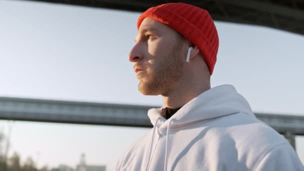 Hombre del deporte usando auriculares para escuchar música en la mañana correr en el parque. Corredor masculino escuchando música móvil en auriculares y corriendo en el parque de verano. Los hombres de fitness en el entrenamiento de la mañana — Vídeo de stock