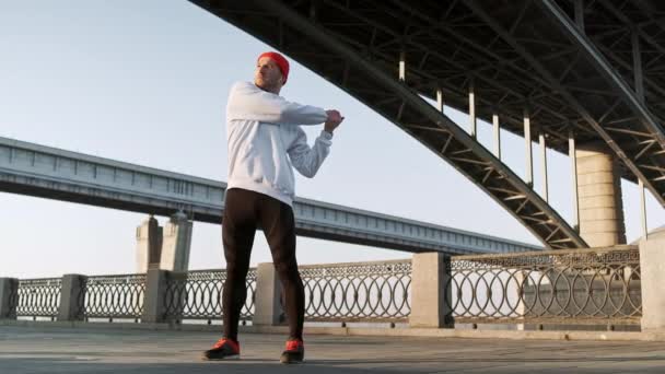 Allenamento uomo stretch urbano. Giovane maschio flessibile si estende profondamente nei dintorni urbani, al rallentatore — Video Stock