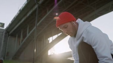 Genç adam günlük rutin egzersiz başlamadan önce onun ayakkabı bağcıkları bağlama. Adam egzersizleri yapıyor ve köprüde koşmak ve Fiziksel fitness testi önce ısınmak.