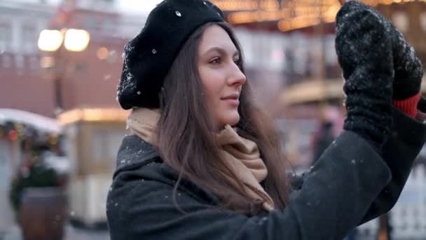 Mujer tomar fotos en la decoración del árbol de Navidad. Una hermosa joven mujer o niña haciendo selfie o usando el teléfono emocionalmente al aire libre frente a las decoraciones navideñas . — Vídeos de Stock