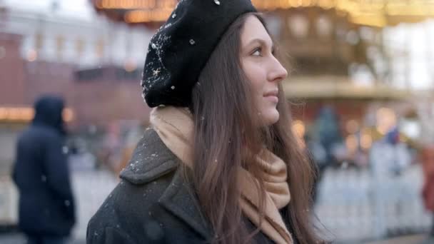 Portret van mooie glimlachende jonge vrouw buiten genieten van winter sneeuwval dragen glazen dop en vacht kijken naar camera. — Stockvideo