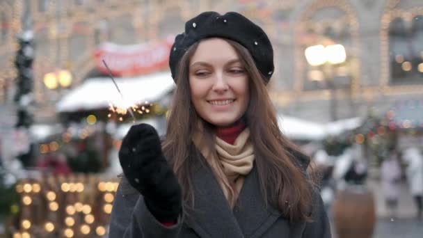 Veselou mladou ženu, která drží jiskrače v ruce venku. Detail dívky oslavující nový rok s bengálním světlem. Closeup překrásné ženy držící na bokeh městech třpytící se hůl — Stock video