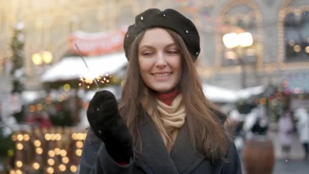 Urlaub, Weihnachten und Menschen-Konzept - junge glückliche Frau im Weihnachtsanzug mit Bengalischem Licht über dem weihnachtlichen Stadthintergrund — Stockvideo