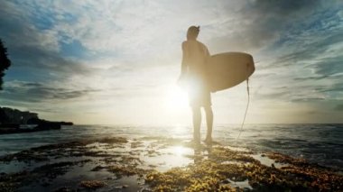 Deniz kıyısında onun elinde duran bir adam ile bir sörf.