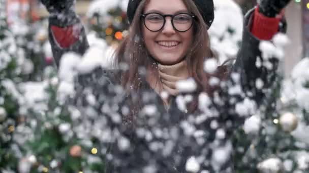Slow Motion: młoda kobieta dmuchanie śniegu. Młoda kobieta dmuchanie śniegu. Portret cute młodej kobiety dmuchanie na śniegu w jej rękach. Rozprasza śnieg w różnych kierunkach — Wideo stockowe