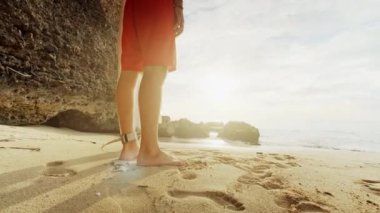 Deniz kıyısında onun elinde duran bir adam ile bir sörf.