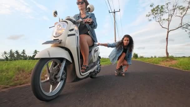 Skateboarder montar cerca de hermosas terrazas de arroz detrás de la motocicleta bicicleta, en Bali, cultura de la actividad indonesia. Mujer guapa va a surfear punto por punto. Surf aventura estilo de vida . — Vídeo de stock