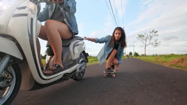 Groupe d'amis patinage et moto. Adolescents joyeux s'amuser à l'extérieur. Deux femmes qui roulent par une journée ensoleillée. Heureux jeune couple s'amuser avec skateboard sur la route . — Video