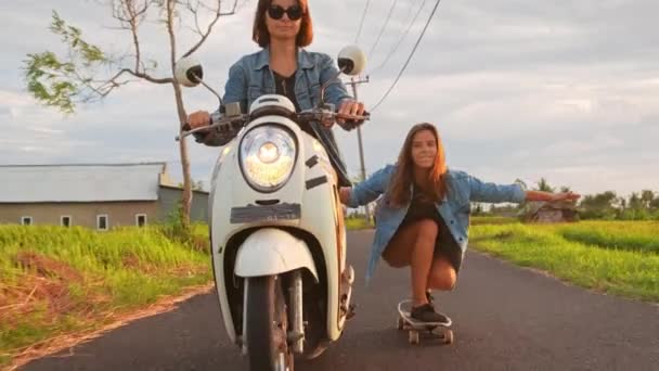 Grupa przyjaciół jazda na łyżwach i motocyklach. Wesołe Nastolatki bawią się na zewnątrz. Dwie kobiety jeżdżą w słoneczny dzień. Szczęśliwy młody para mający zabawa z deskorolka na The droga. — Wideo stockowe