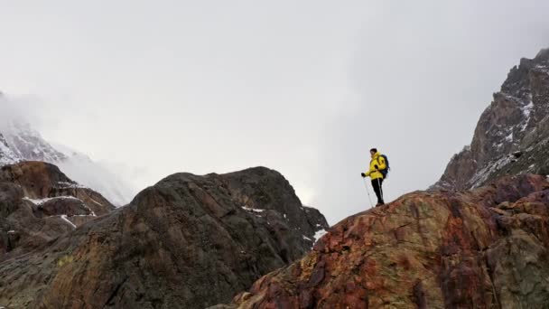 Turista en la cima de la montaña. Deporte y vida activa. Caminante con mochila de pie en la cima de una montaña y disfrutando del amanecer. Joven excursionista en el pico de la montaña al atardecer Exitoso — Vídeo de stock