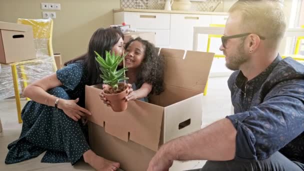 Mutlu karışık etnik familye açık açma karton kutu parsel tehcir yenileme sonra iç tasarım dekor tartışırken, aile oturma odasında kanepede oturan — Stok video