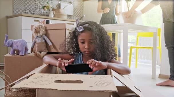 Familia feliz se muda a un nuevo apartamento. bebé feliz en una caja de cartón — Vídeo de stock