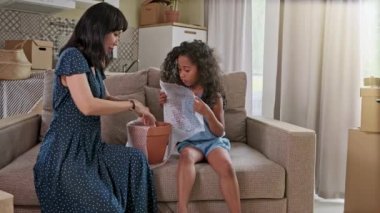 Mutlu karışık etnik familye açık açma karton kutu parsel tehcir yenileme sonra iç tasarım dekor tartışırken, aile oturma odasında kanepede oturan