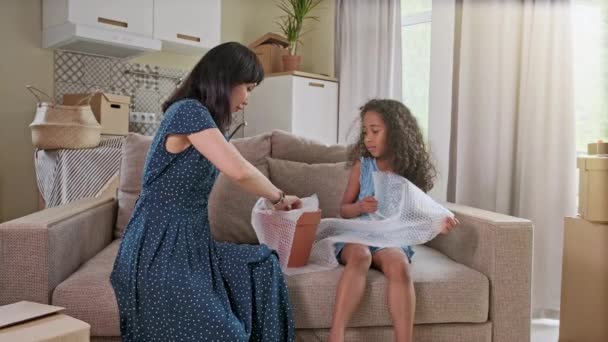 Happy black family with little kid move relocate at new home gather in living room unpack belongings stuff from cardboard boxes — Stock Video