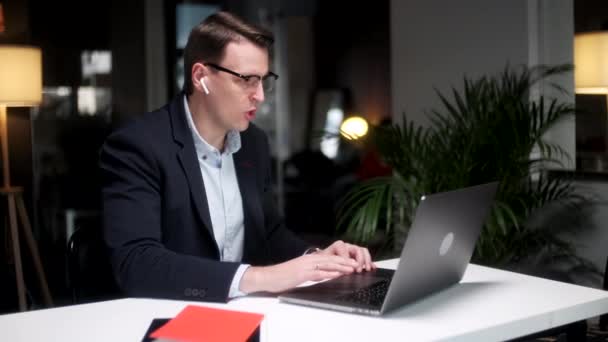 Business Man Mówienie na wideokonferencji online w biurze. Przystojny pracownik ma połączenie wideo na laptopie w domu. mężczyzna profesjonalne wyjaśnienie projektu z gestów w odległym miejscu pracy — Wideo stockowe