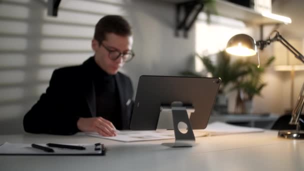 Business Man Engineer werkt met blauwdrukken en laptop in de moderne werkplek. Knappe man is glazen werken in een modern kantoor Interieur werkplek, Op zoek geconcentreerde en zelfverzekerde. — Stockvideo