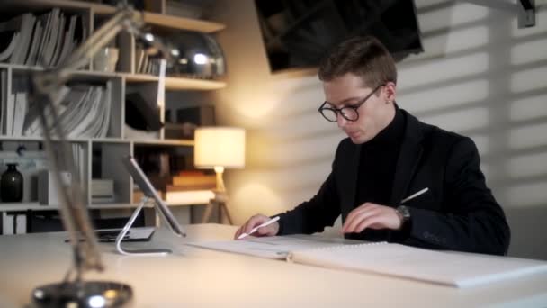 Arquitecto trabajando en la oficina. Dibuja con pluma o herramientas en la tableta. Retrato de negocios de hombre de negocios guapo con anteojos sentados en el lugar de trabajo. Empresario de confianza se convirtió en un éxito . — Vídeos de Stock