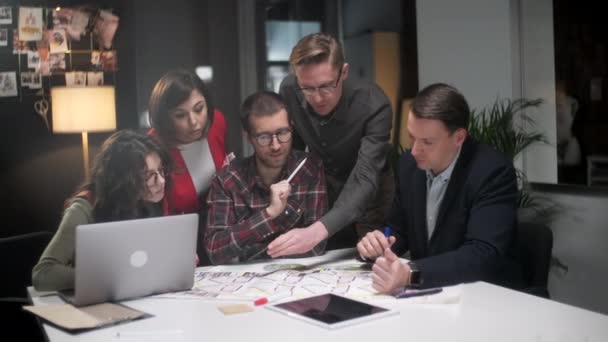 Equipe de arquitetos que trabalham no projeto Paper Blueprint. Grupo de empresários modernos em desgaste casual discutindo projetos arquitetônicos enquanto se senta no escritório criativo . — Vídeo de Stock