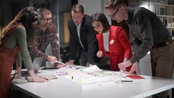 Team Of Architects Working On Project Paper Blueprint. Groupe de gens d'affaires modernes dans l'usure occasionnelle Discuter des conceptions architecturales tout en étant assis dans le bureau créatif.