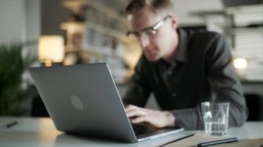 İnternette Laptop kullanan, internette çalışan, bilgisayar sörfü yapan, bilgisayarlı internette gezinen, bilgisayardan keyif alan, internetteki işine odaklanmış, gülümseyen genç adam.