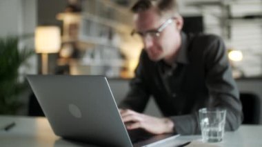 İnternette Laptop kullanan, internette çalışan, bilgisayar sörfü yapan, bilgisayarlı internette gezinen, bilgisayardan keyif alan, internetteki işine odaklanmış, gülümseyen genç adam.