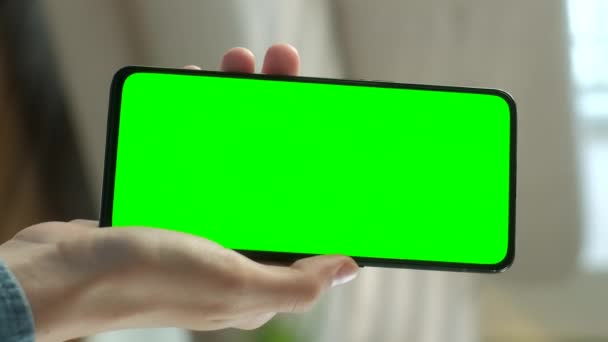 Close-up shot van jonge vrouw thuis zitten op een stoel met behulp van Green Mock-up Screen Smartphone. Meisje kijkt naar inhoud zonder het aanraken van gadget scherm. Met verticale schermoriëntatie 9: 16 — Stockvideo