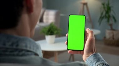 Green Mock-up Smartphone kullanarak Evdeki Genç Adam 'ın Bir Sandalyede Oturması. Çocuk 