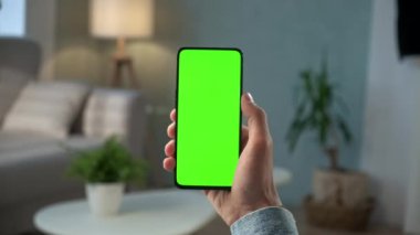 Modern Odada Bir Kadın Oturuyor Yeşil Model Ekran Krom Anahtarı ile Telefon Kullanıyor İnternet İzleme İçeriği Videoları Blog 'ları İzlemeden. Yukarı Kaydır
