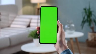 Telefondaki kadının POV görünümü ve kopyalama alanı için yeşil ekran. Chromakey İşaretlemesiz Mock Up. 20 'li yaşlardaki Bayan Kanepe Kapanış' ta Video Haberleri izliyor. Ekran Merkezine Tıklanacak Tıklama