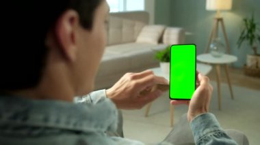 Uzayı Kopyalamak için Yeşil Ekranlı Telefondaki Kadın Görünümü. Chromakey İşaretlemesiz Mock Up. 20 'li yaşlardaki Bayan Kanepe Kapanış' ta Video Haberleri izliyor. Yukarı Kaydır