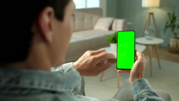 Visão traseira da mulher no telefone com tela verde para espaço de cópia. Chromakey Mock Up sem marcadores de rastreamento. 20s Lady assistindo vídeo notícias no sofá de perto. Deslize para cima — Vídeo de Stock