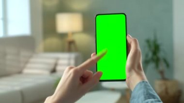 Telefondaki kadının POV görünümü ve kopyalama alanı için yeşil ekran. Chromakey İşaretlemesiz Mock Up. 20 'li yaşlardaki Bayan Kanepe Kapanış' ta Video Haberleri izliyor. Çifte Geçiş
