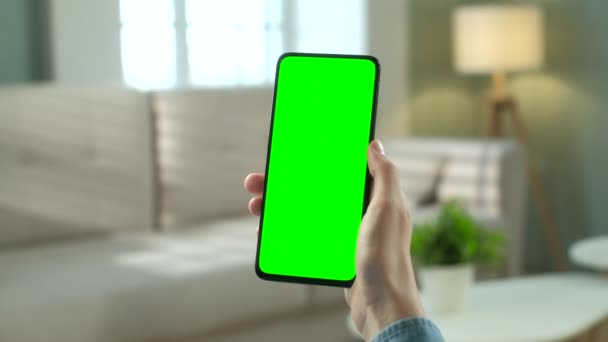 Vista de cerca de la mujer en la habitación moderna sentada en una silla usando el teléfono con Green Mock-up Screen Chroma Key sin puntos de seguimiento Navegar por Internet Ver contenido Videos Blogs. Doble deslizamiento hacia arriba — Vídeo de stock