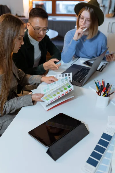 En grupp unga designers samlades på kvällen på kontoret för att diskutera idéer — Stockfoto