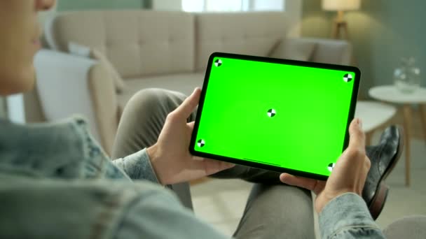 View From the Shoulder of Man Holding and Using Hand Gestures on Green Mock-up Screen Ψηφιακός υπολογιστής tablet Καθισμένος σε μια καρέκλα. Αρσενικό Αγορά πράγματα ή Περιήγηση μέσω του Διαδικτύου. — Αρχείο Βίντεο