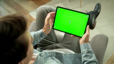 Green Mock-up Tablet Dijital Tablet Bilgisayarında Erkek Tutma ve El Hareketleri Kullanma Omuzundan Görünüm. Erkek alışverişi ya da göz gezdirme. Orta Ekranda Tıklama