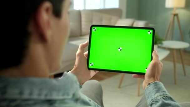 View From the Shoulder of Man Using Hand Gestures on Green Mock-up Screen Ψηφιακός υπολογιστής tablet σε λειτουργία τοπίου, ενώ κάθεται σε μια καρέκλα. Στο φόντο άνετο σαλόνι. — Αρχείο Βίντεο