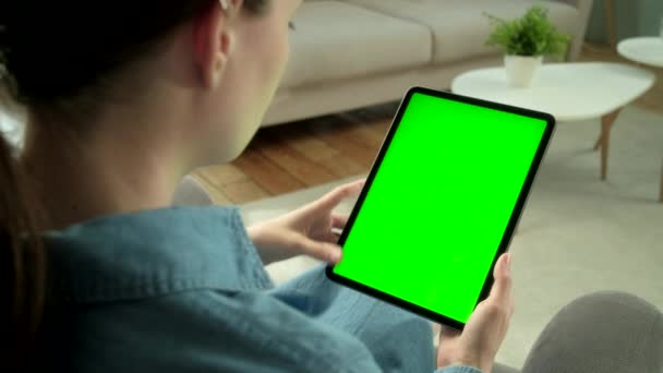 View From the Shoulder of Woman Using Hand Gestures on Green Mock-up Screen Digital Tablet Számítógép függőleges módban, miközben ül egy széken. A háttérben Hangulatos nappali. — Stock videók