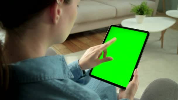 女性の肩からの眺め緑のモックアップ画面に手のジェスチャーを使用してデジタルタブレットコンピュータ椅子に座っています。女の子は物を買うか、インターネットを通して閲覧. — ストック動画