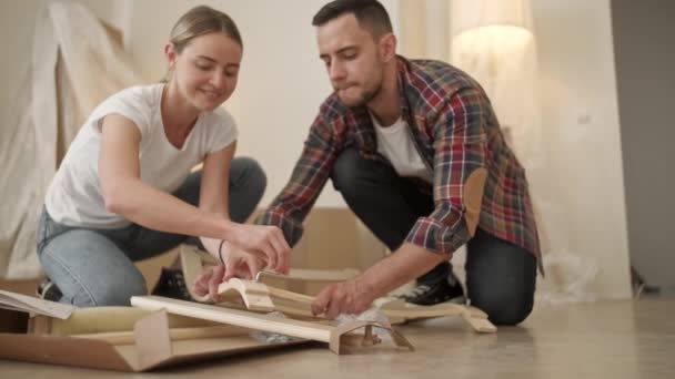 Adultos jóvenes mudándose a un nuevo hogar. Pareja moviéndose en el montaje de muebles de silla. Joven pareja interracial en un nuevo hogar. reparación, renovación y concepto de personas — Vídeos de Stock