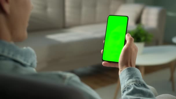 Zurück Ansicht von Brunette Man Holding Chroma Key Green Screen Smartphone Inhalte beobachten, ohne zu berühren oder zu wischen. Junge benutzt Handy, surft im Internet, schaut sich Inhalte, Videos, Blogs an. — Stockvideo