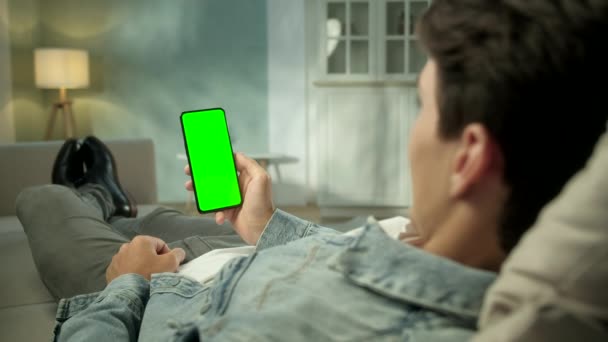 Back View of Brunette Man Holding Chroma Key Green Screen Smartphone Watching Content Without Touching or Swiping. ( 영어 ) Boy Using Mobile Phone, Browsing Internet, Watching Content, Videos, Blogs. — 비디오