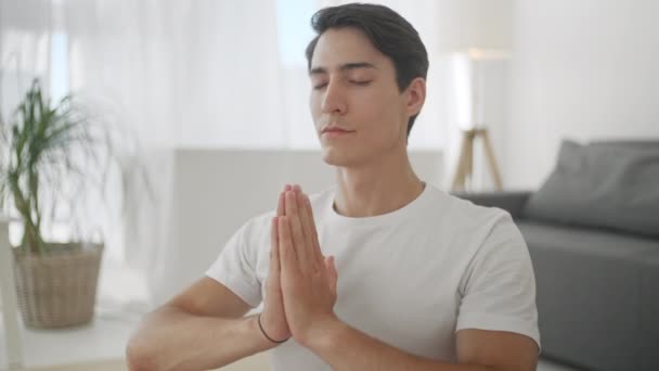 Close Up Guy Fazendo Yoga em casa Mantendo os olhos fechados Respirando lentamente. Desporto em casa e estilo de vida saudável, atividade, fitness e exercício. Treinamento interno e exercício em casa — Vídeo de Stock