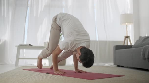 Junger Mann praktiziert Yoga zu Hause: Er macht Bakasana. Einfache Balance Yoga Asana Gesunder Rücken Langsam — Stockvideo