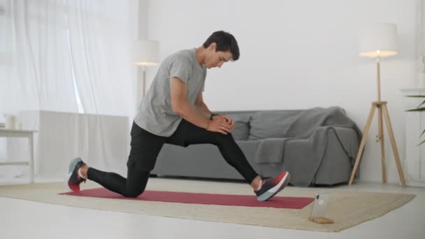 Deportivo Caucásico Hombre Entrenando, Haciendo Cross Fit Ejercicio Deportivo en Carpé Mientras Ver Fitness Video En Línea En Teléfono En Casa . — Vídeos de Stock