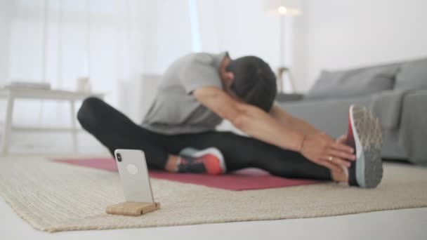 Deportivo Caucásico Hombre Entrenando, Haciendo Cross Fit Ejercicio Deportivo en Carpé Mientras Ver Fitness Video En Línea En Teléfono En Casa . — Vídeos de Stock